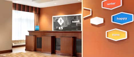 A reception area with a wooden reception desk, a large framed sign with a pedestrian crossing and 'travel.' text, and hexagonal wall decorations with 'enter,' 'happy,' and 'zone' text.