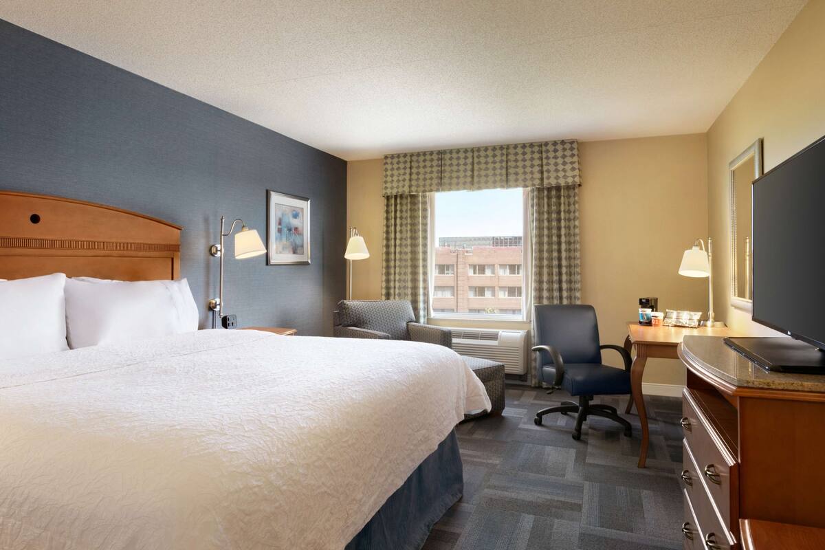 Une chambre d’hôtel avec un grand lit, un bureau avec un ordinateur, une chaise et un téléviseur.