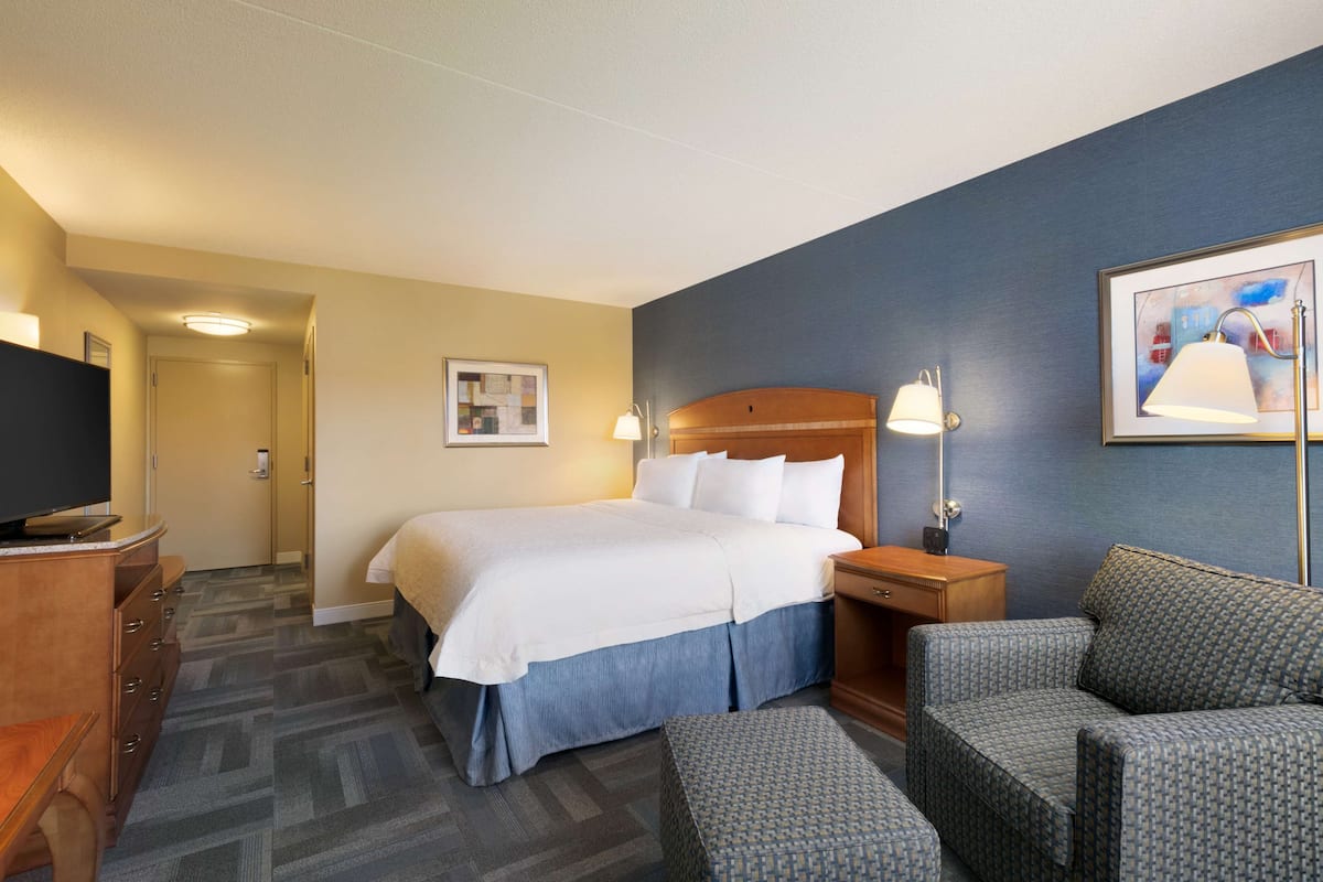 Une chambre d’hôtel comprenant un lit, un bureau avec une télévision, une chaise et une lampe.
