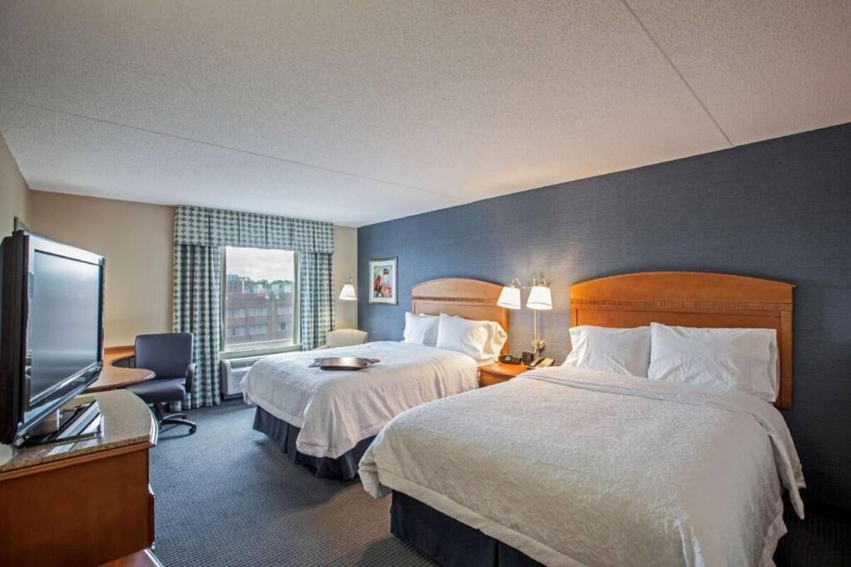 Une chambre d’hôtel avec deux lits, une télévision, un bureau et une fenêtre donnant sur la ville.