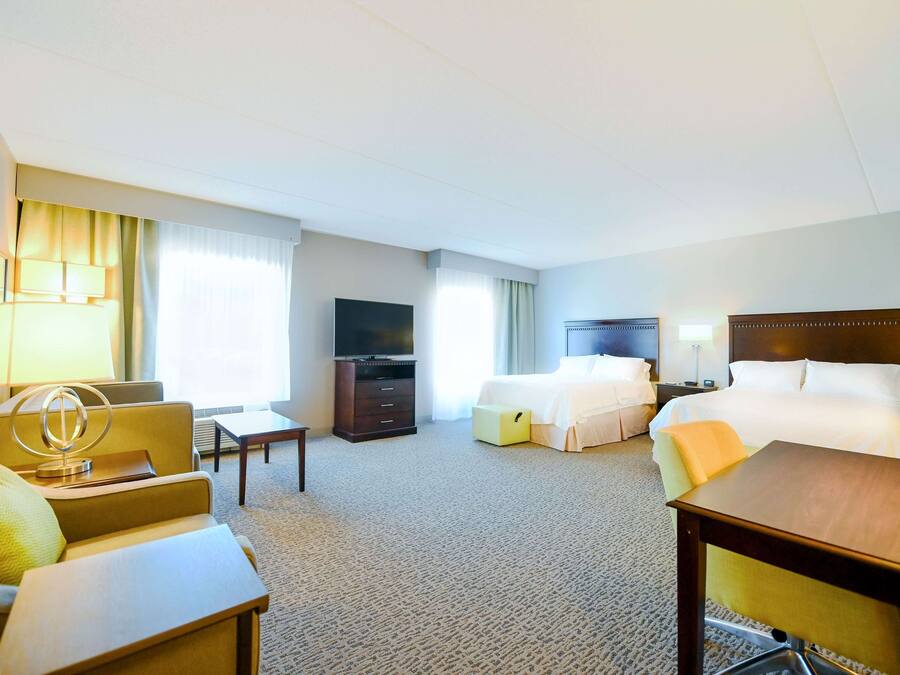 Ein Hotelzimmer mit Bett, Schreibtisch, Stuhl, Fernseher und Lampe.