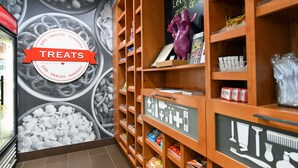 Una sección de aperitivos y artículos varios con estantes llenos de diversas golosinas y un mural que representa alimentos.
