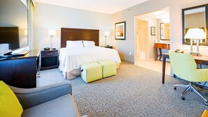 Habitación de hotel con cama, mesitas de noche, escritorio, silla y baño visible a través de una puerta abierta.