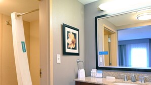Un baño con ducha, un lavabo con espejo y un cuadro en la pared.