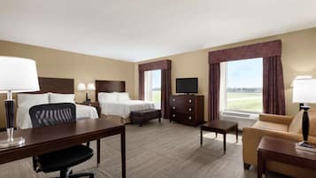 A hotel room with a bed, desk, chair, television, and a sofa.