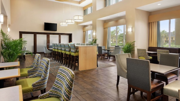 A hotel lobby with a bar area, seating arrangements, and large windows providing natural light.