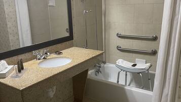 A bathroom with a sink, mirror, shower, and bathtub.