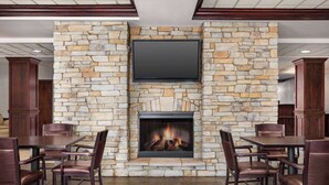 Una chimenea de piedra con un televisor de pantalla plana en la parte superior, flanqueada por mesas y sillas de comedor.