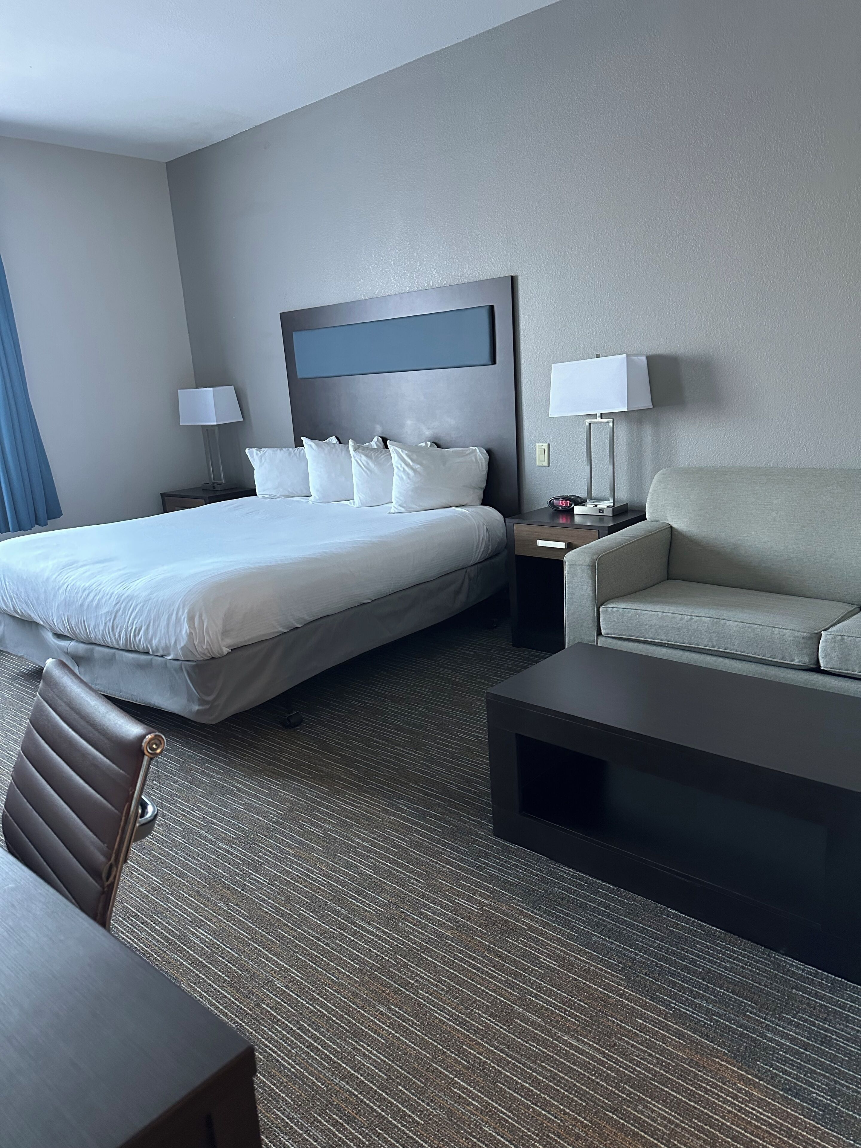 A hotel room with a large bed, a sofa, a desk, and two bedside tables.