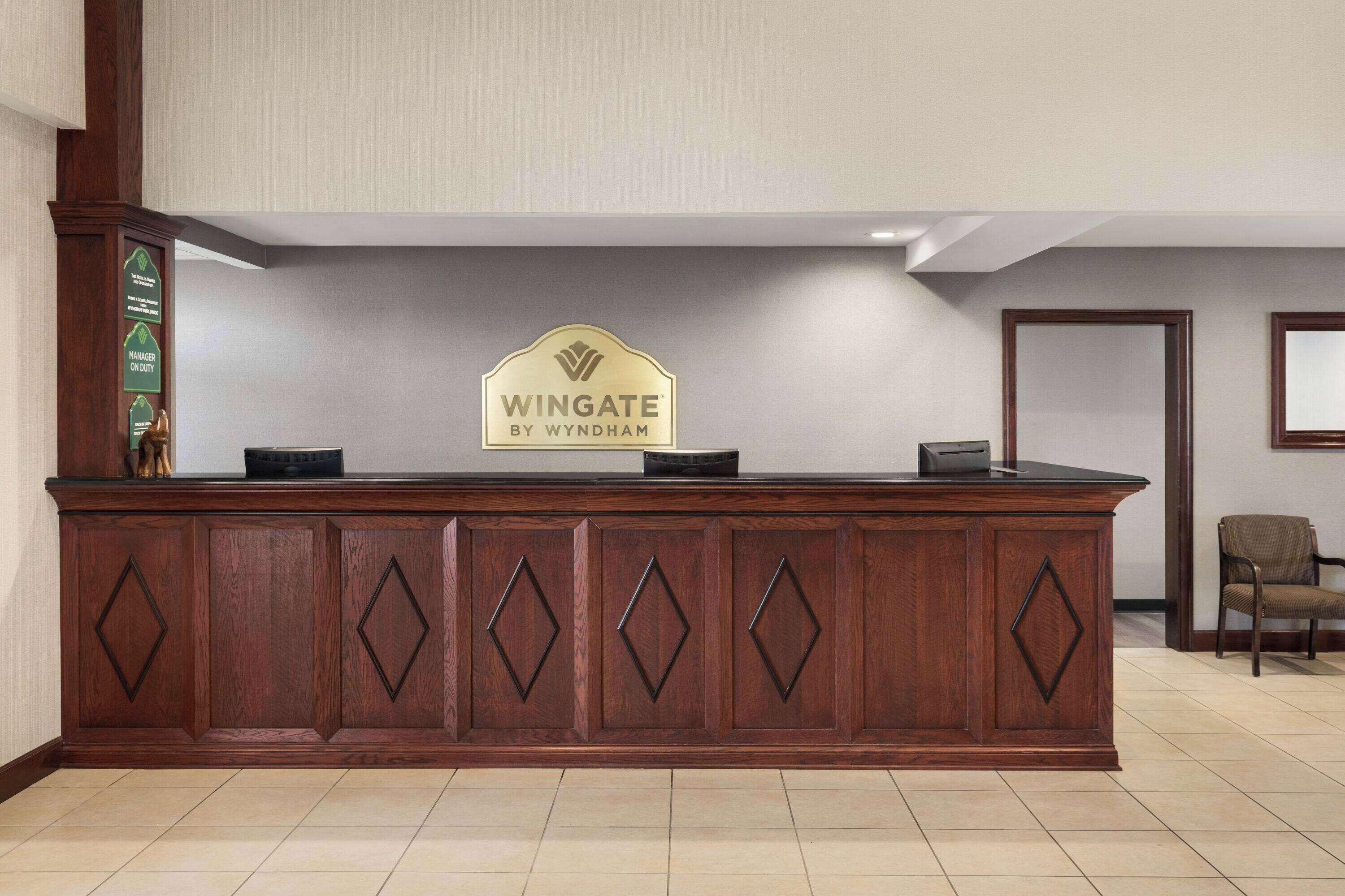 Vastaanottotiski, jossa on kyltti, jossa lukee: ”Wingate by Wyndham”.