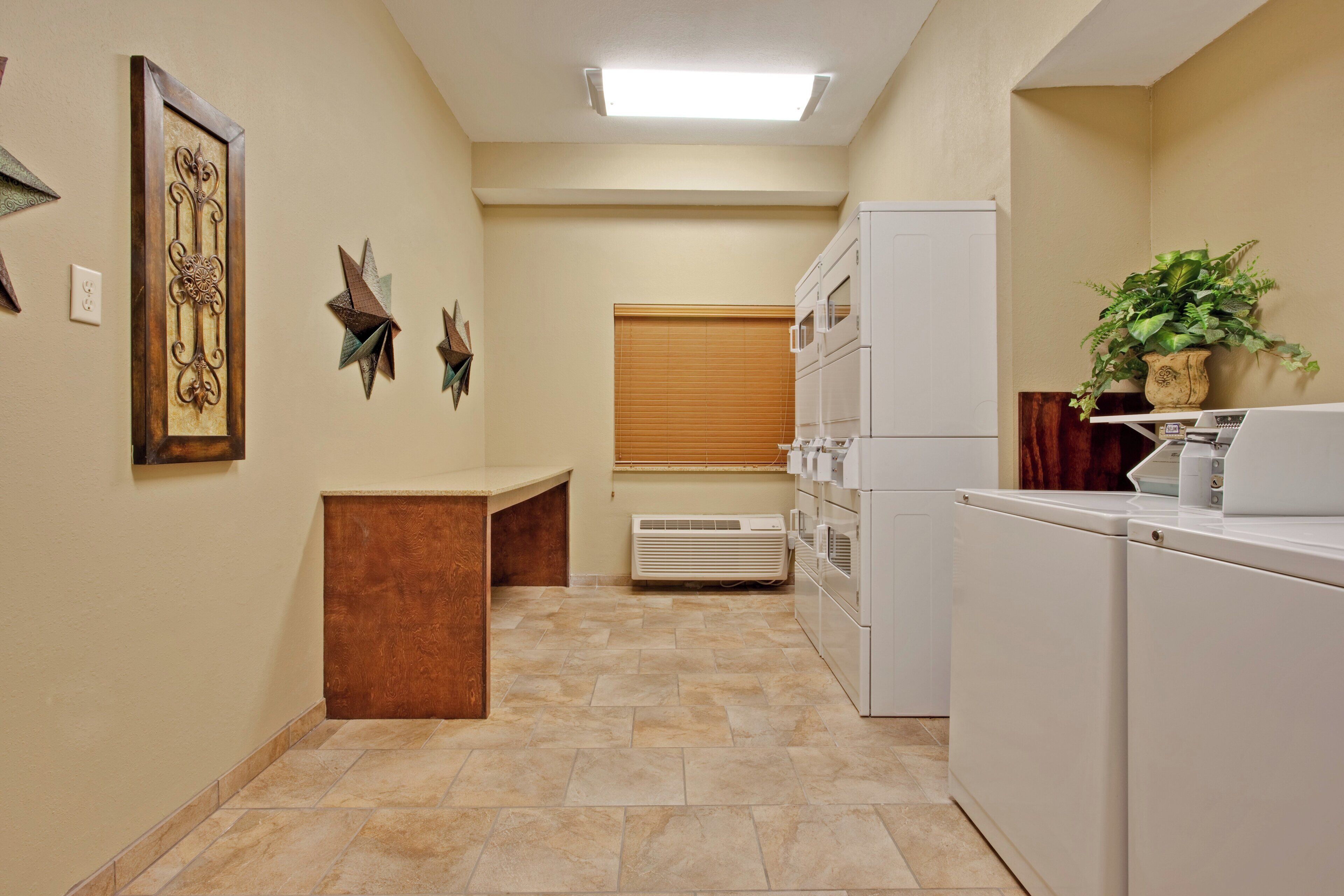 A laundry room with a bench, a wall-mounted heater, and a potted plant.