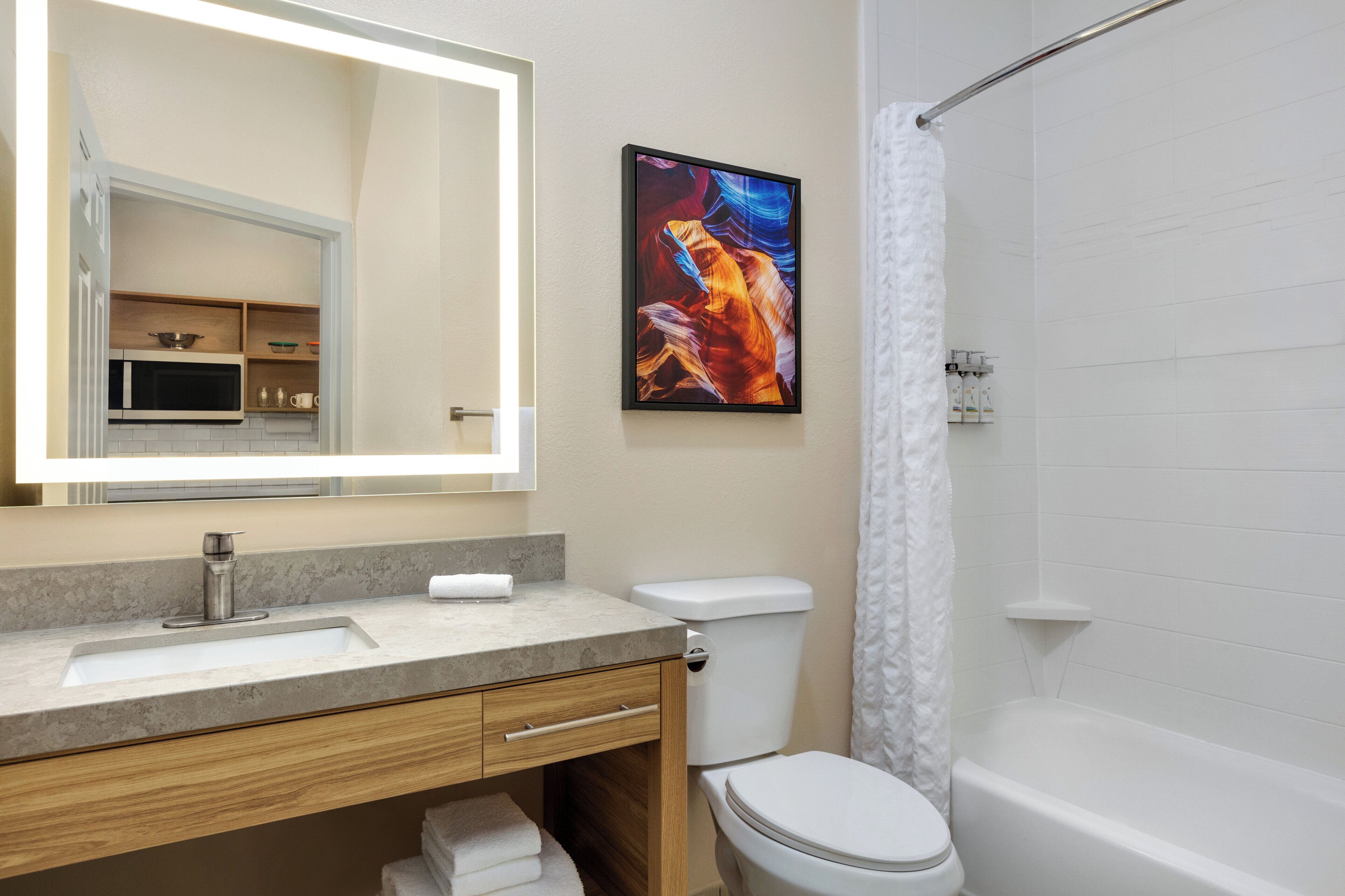 A modern bathroom with a sink, mirror, toilet, and bathtub.