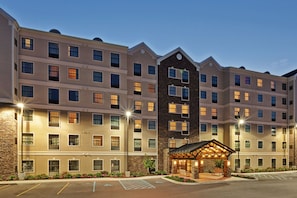 A multi-story hotel with a central courtyard, large windows, and a well-lit entrance. - Staybridge Suites West Seneca by IHG (Buffalo)
