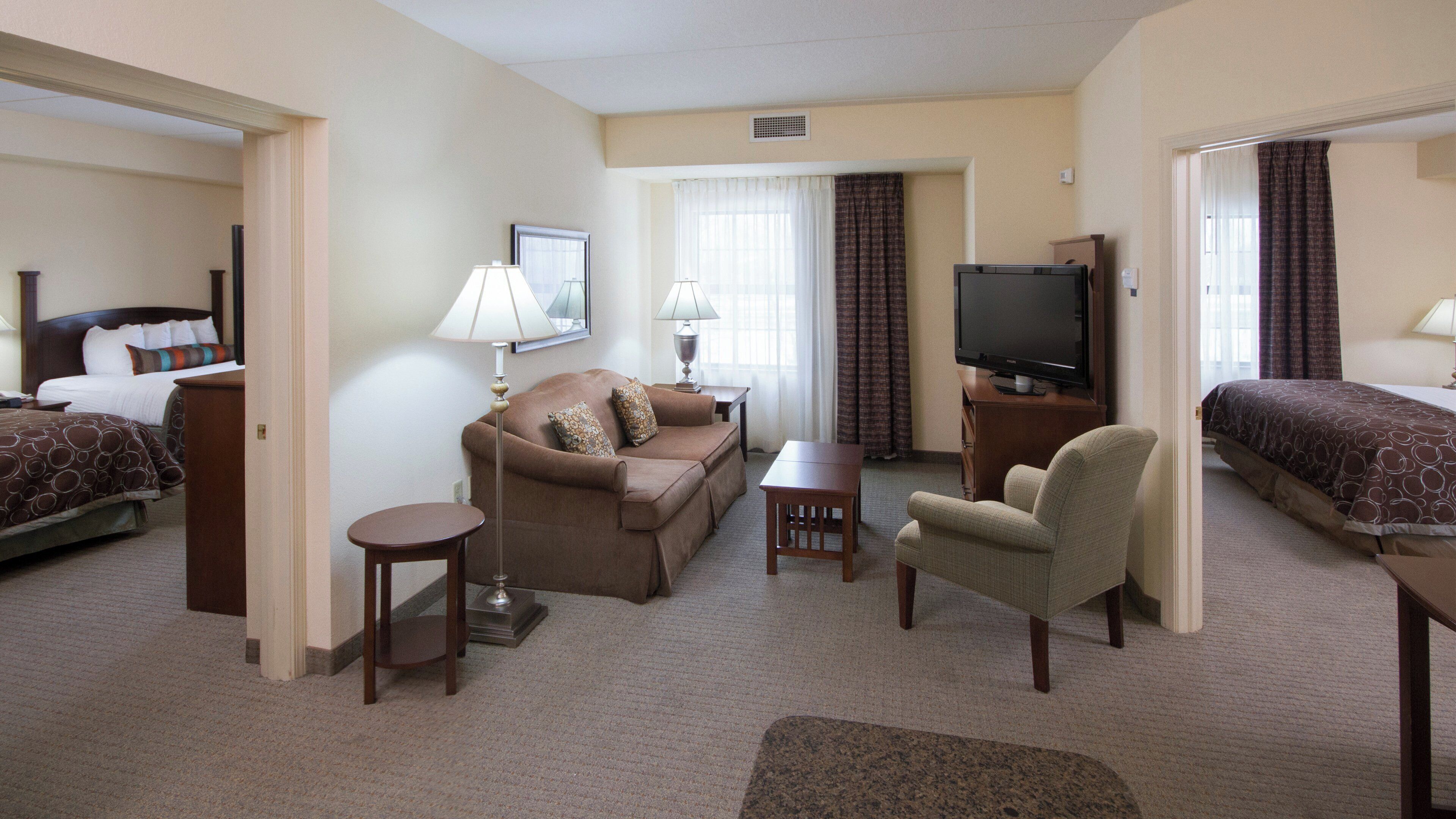 Una habitación de hotel con una cama, un sofá, una silla, un televisor y un escritorio.