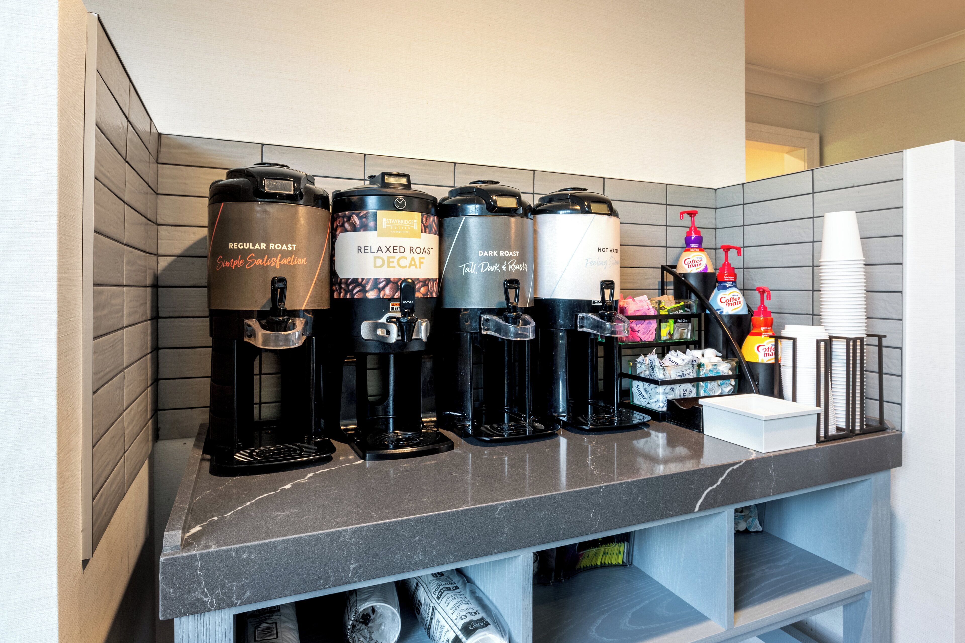 A coffee station with four different types of coffee machines and a variety of coffee dispensers.