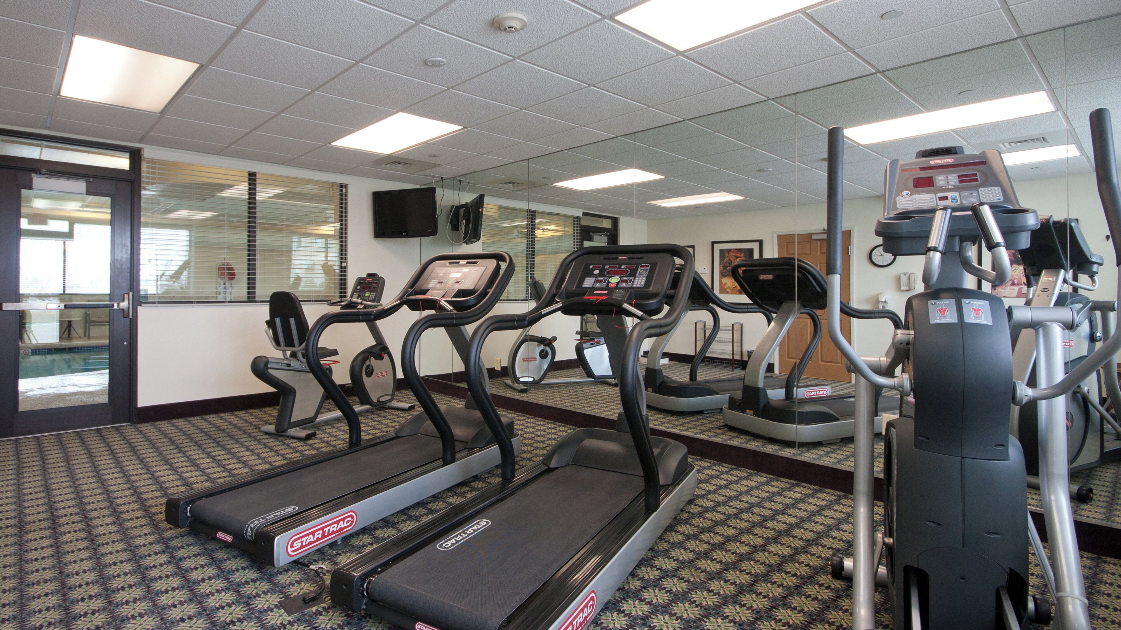 Un gimnasio equipado con cintas de correr, elípticas y una bicicleta estática.