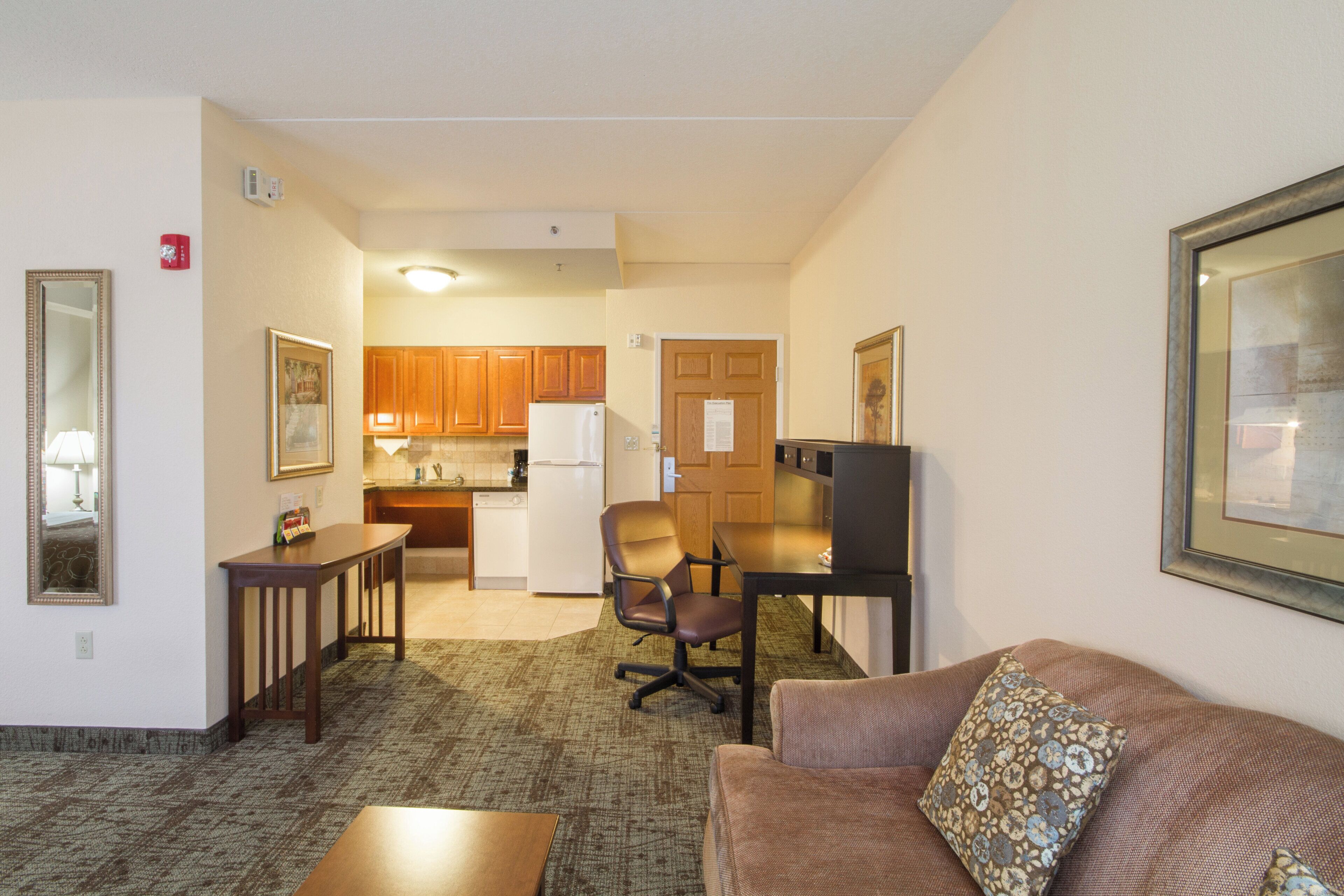 A compact living space with a kitchenette, a dining area, and a seating area with a couch and a TV.