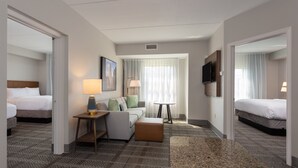 A hotel room with a bed, a sofa, a table, and a TV. - Staybridge Suites West Seneca by IHG (Buffalo)