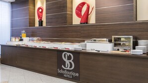 A buffet counter with a SoHoBoutique Hotels sign, various food items, and a coffee machine. - Hotel ITC Salamanca by Soho Boutique (Salamanca)