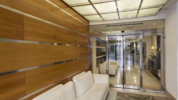 A modern lobby with a wooden panel wall, a white sofa, and a glass door leading to a well-lit interior. - Hotel ITC Salamanca by Soho Boutique (Salamanca)