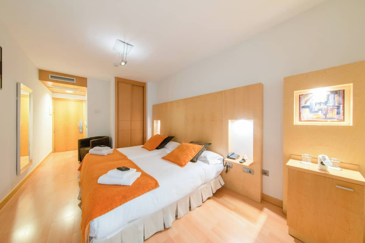 Une chambre d’hôtel avec un grand lit, une table de chevet avec une lampe, une armoire en bois et un miroir au mur.
