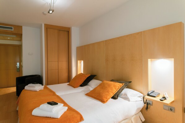 A hotel room with two beds, a desk, a phone, and a mirror.