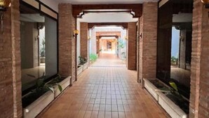 A corridor with tiled flooring, brick walls, and large windows on both sides. - Las Tablas (Daimiel)