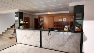 Un espace d’accueil doté d’un comptoir en marbre, d’un téléphone et d’affiches d’information.