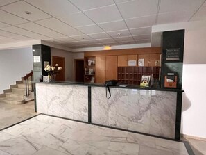 A reception area with a marble counter, a phone, and informational posters. - Las Tablas (Daimiel)