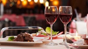 A dining table with a plate of steak and vegetables, two glasses of red wine, and a candle. - Las Tablas (Daimiel)