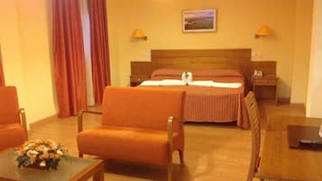 Una habitación de hotel con una cama, dos mesitas de noche, un escritorio y dos sillas.