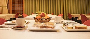 A breakfast setting with a fruit basket, bread, and pastries on a table. - Las Tablas (Daimiel)