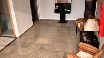 A lobby with a reception desk, a map display, and wicker chairs.