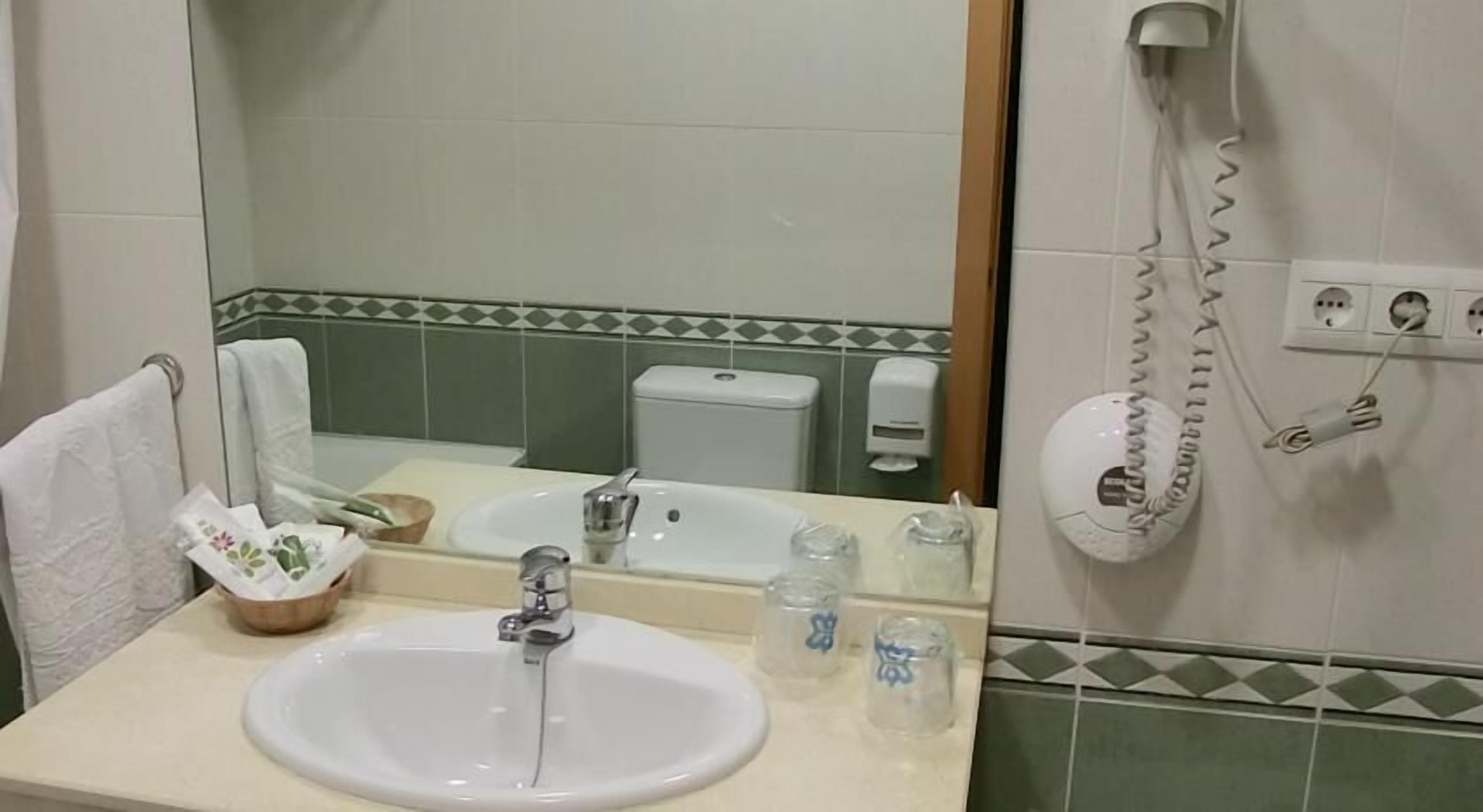 A bathroom with a white sink, mirror, and a hairdryer mounted on the wall.