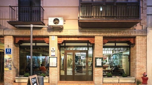 A restaurant with a brick facade, large glass windows, and a sign above the entrance. - Las Tablas (Daimiel)