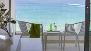 A balcony with two white chairs, a small round table, a green bottle, and a glass of water. - Silver Sands Beach Hotel (Paralimni)