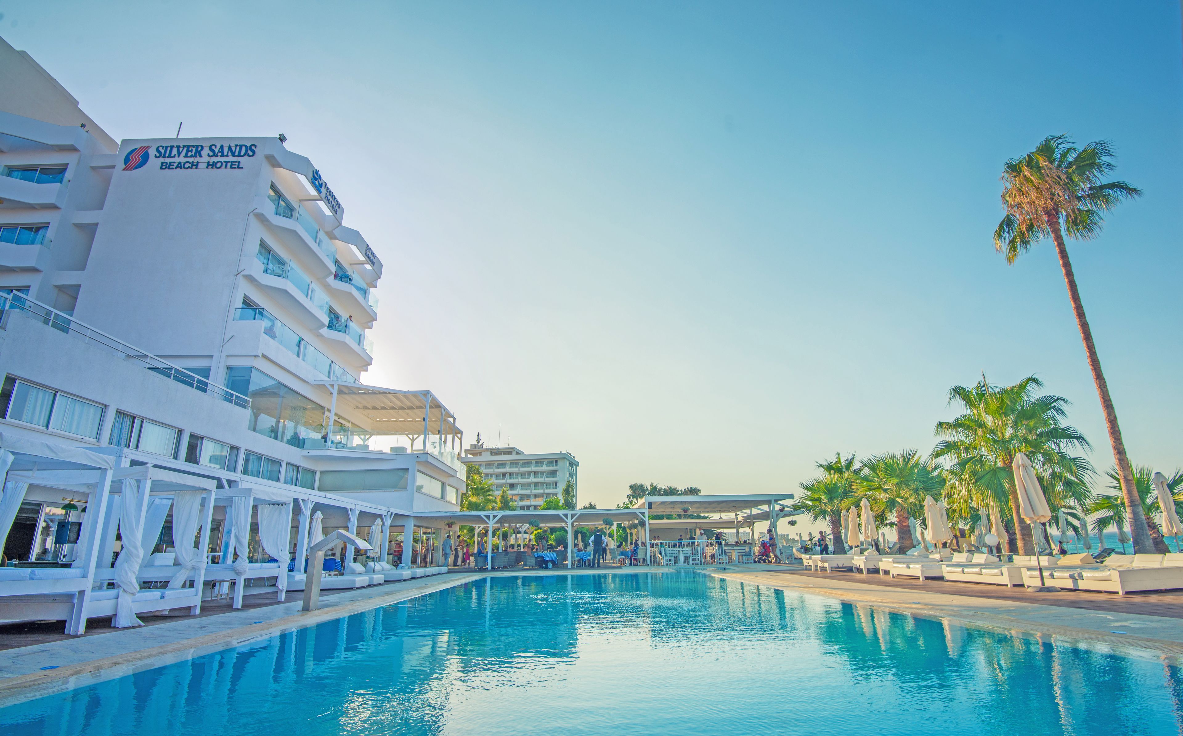 Un hotel con piscina, palmeras y cielo despejado.