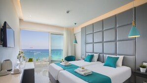 A modern hotel room with a large bed, a desk with a coffee maker, and a view of the ocean. - Silver Sands Beach Hotel (Paralimni)