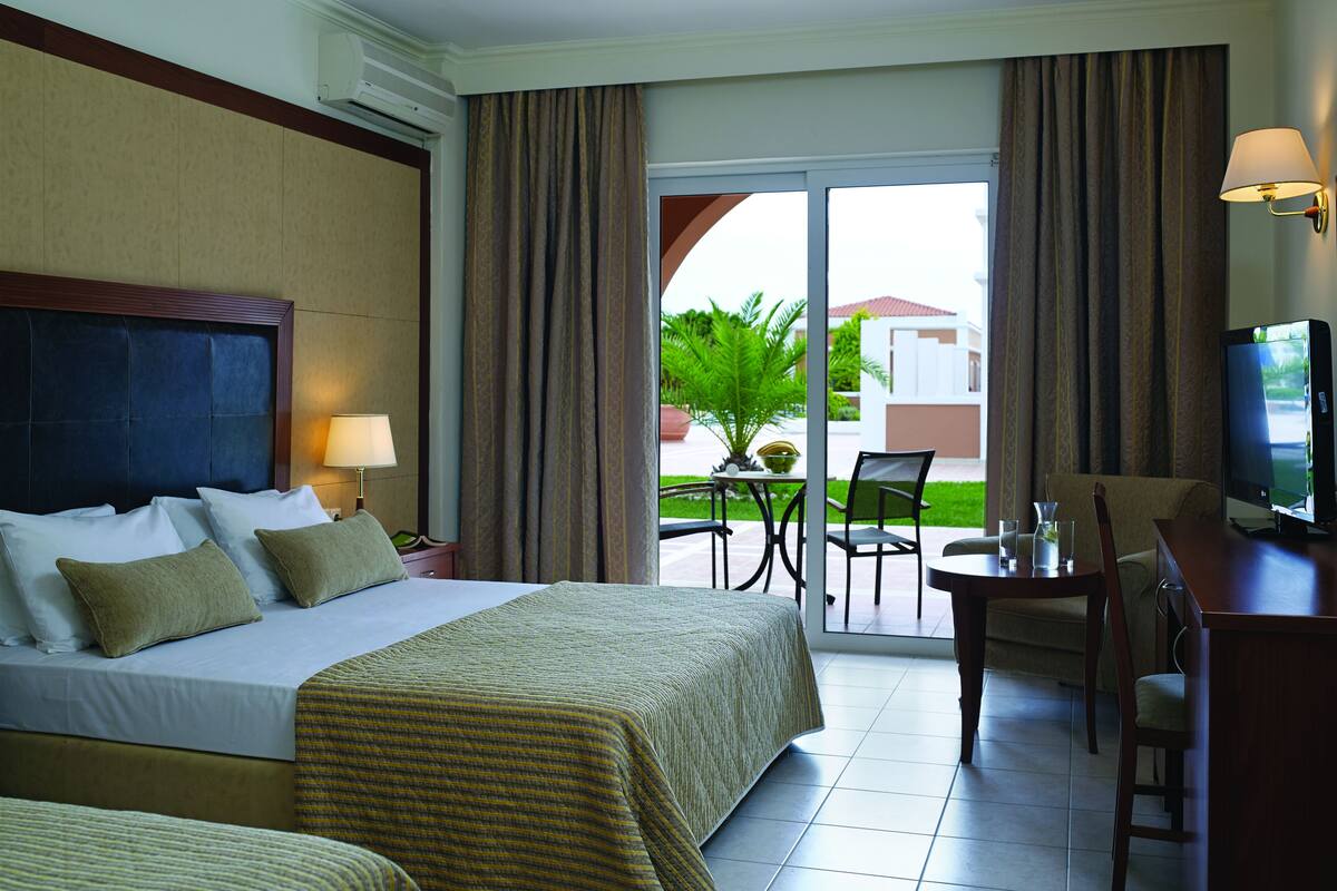A hotel room with a bed, a desk, a chair, and a television.
