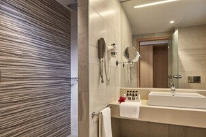 Un baño moderno con un espejo grande, un lavamanos y un secador de pelo montado en la pared.