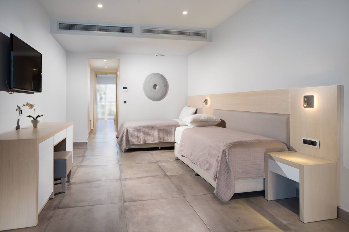 A modern hotel room with a bed, bedside tables, a desk, and a TV.