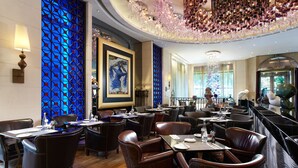 Un restaurante con sillas de cuero, mesas y una pared con estampado azul.