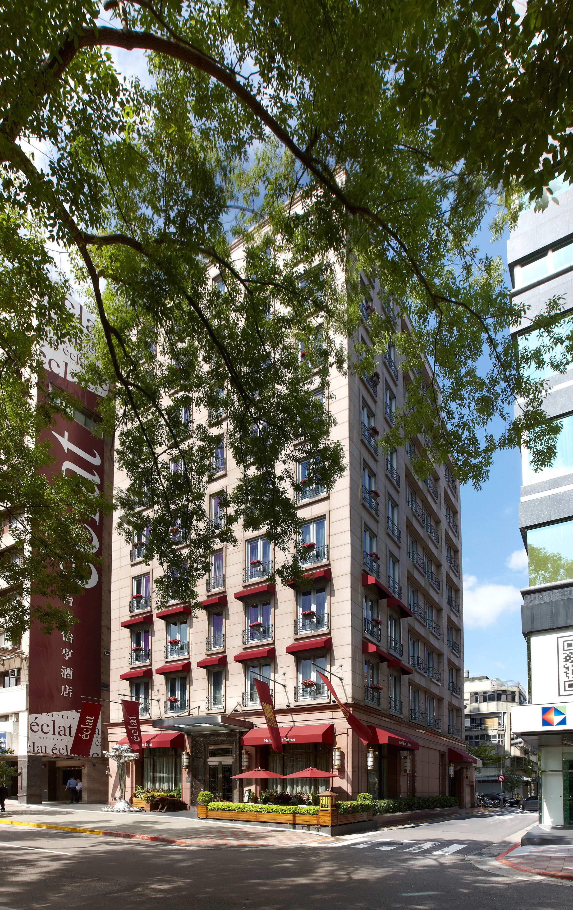 Un hotel de varios pisos con balcones, toldos rojos y un letrero vertical grande.