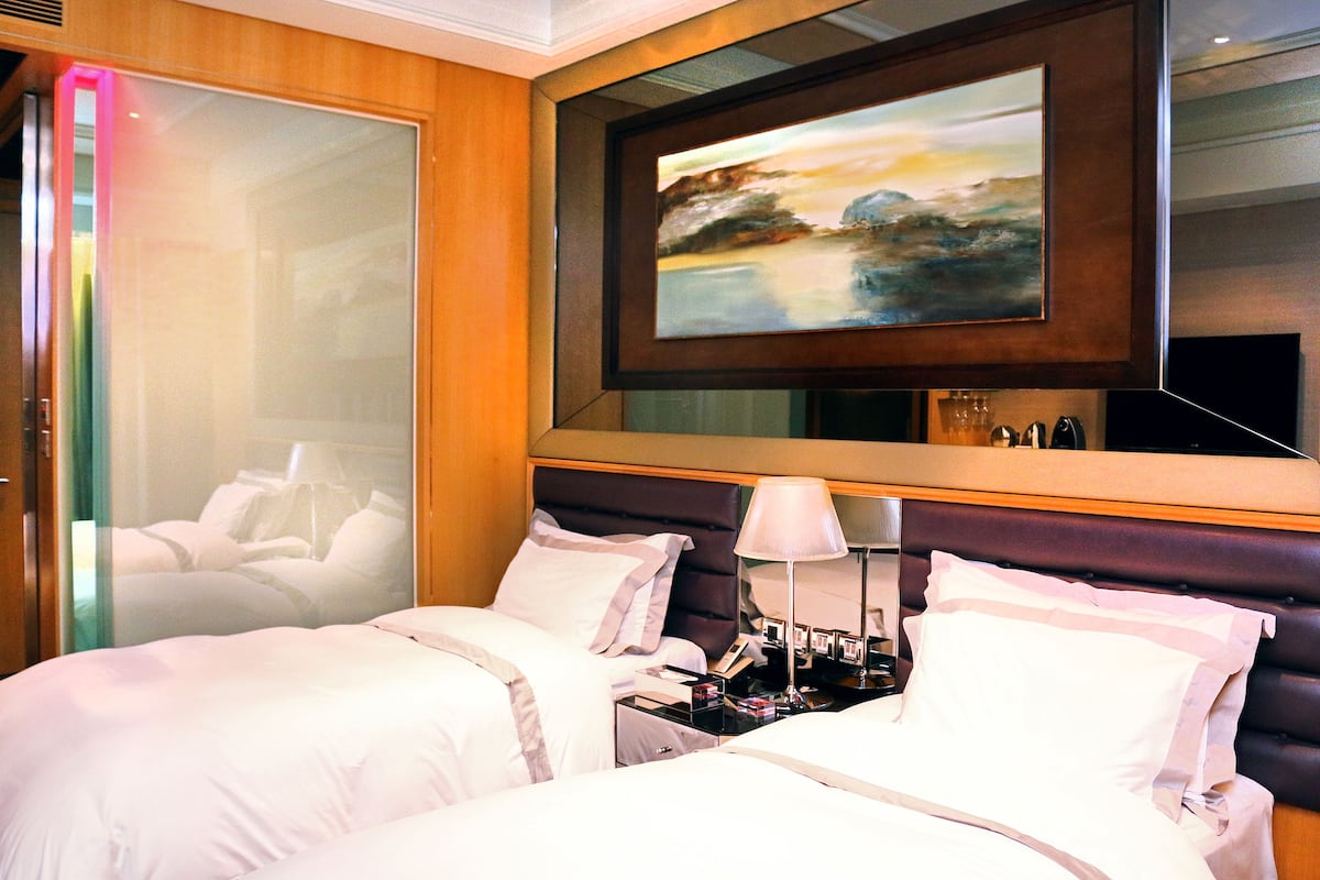 A hotel room with a large bed, a nightstand, a lamp, and a painting on the wall.