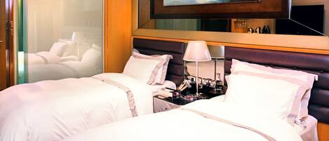A hotel room with a large bed, a nightstand, a lamp, and a painting on the wall.