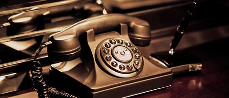 A vintage rotary dial telephone on a wooden surface.