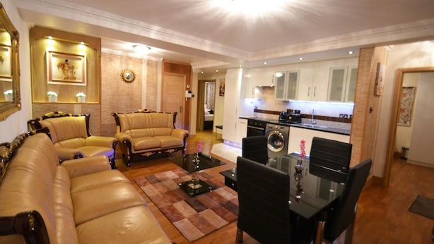 A living room with a sofa set, a dining table with chairs, and a kitchen area with cabinets and appliances.