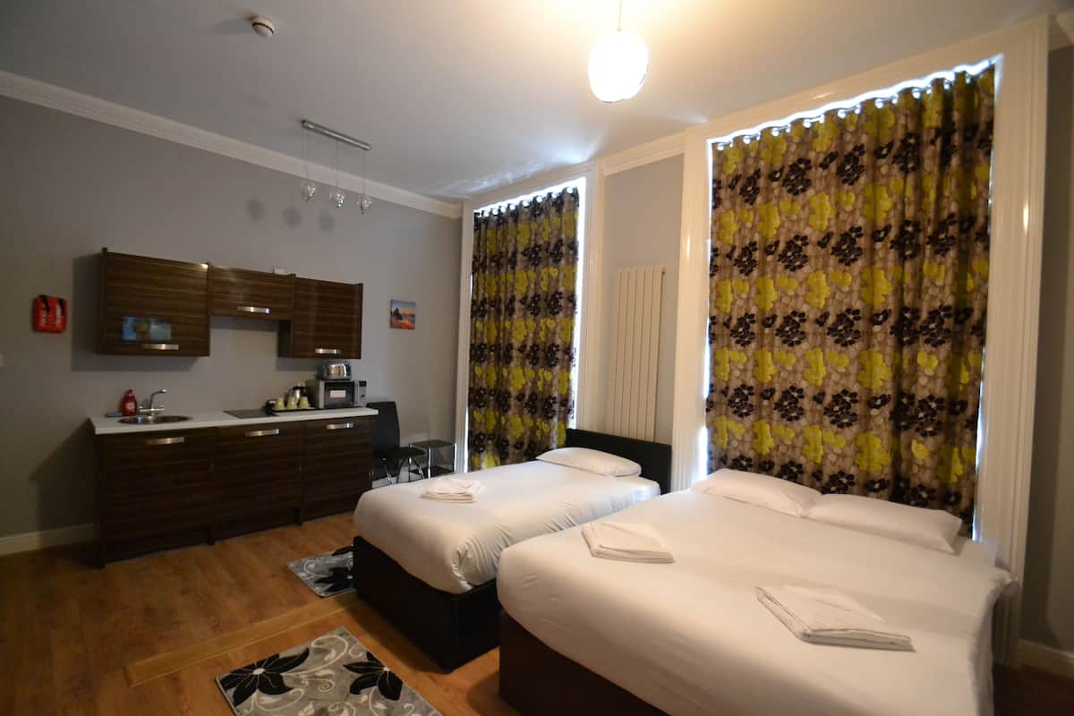 Ein Hotelzimmer mit zwei Betten, einer Küchenzeile, einem Badezimmer und Blick auf die Stadt.