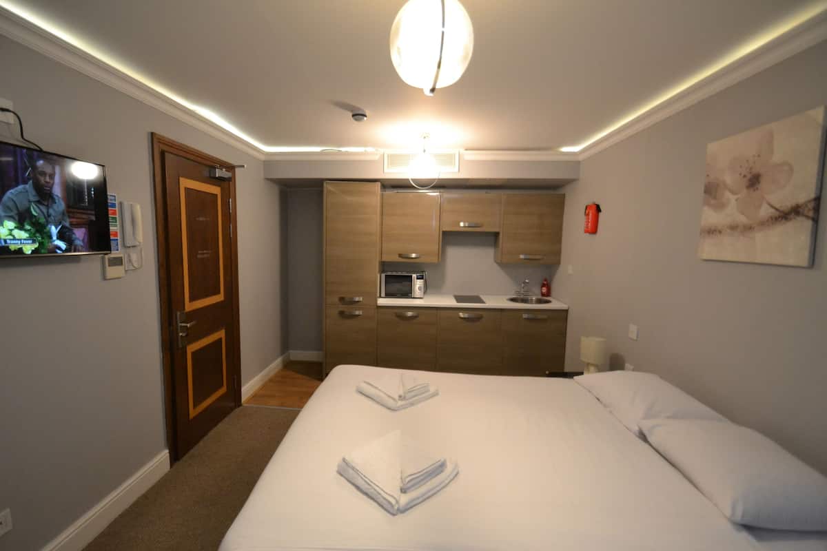 Ein Hotelzimmer mit einem Bett, einem Fernseher, einer Küchenzeile und einer Tür.