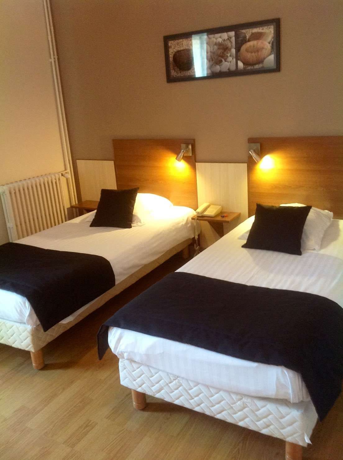 Two single beds with headboards, bedside tables, and lamps.
